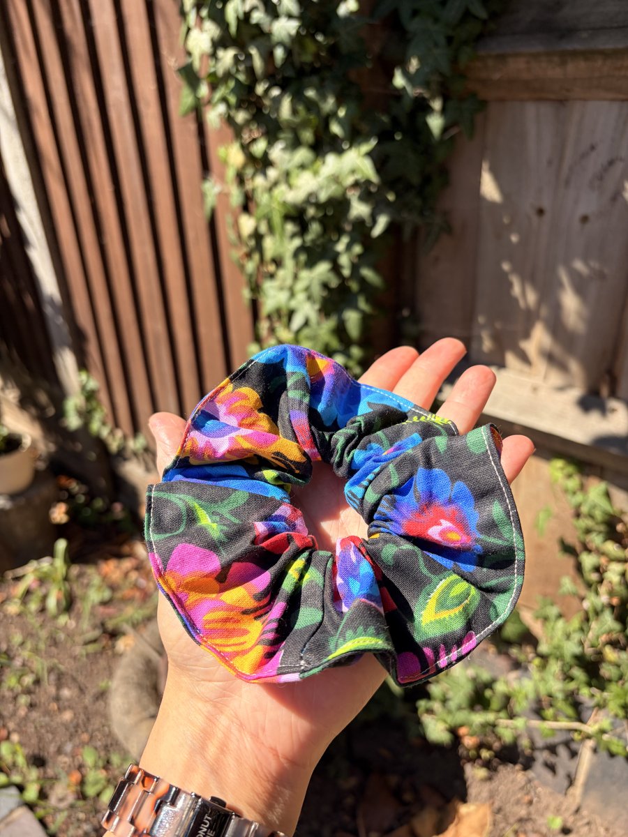 Handmade floral scrunchie held in a hand outdoors in the sunshine