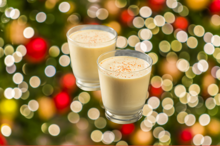 Two glasses of ponche de crema venezolano in front of Christmas tree lights